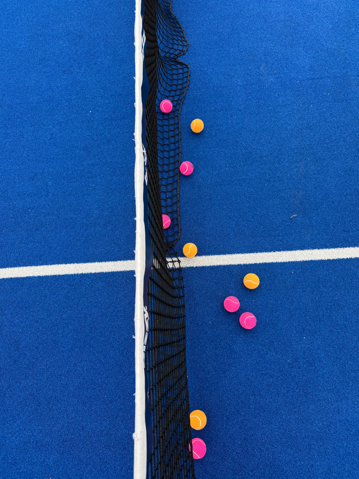 gekleurde padelballen op het veld